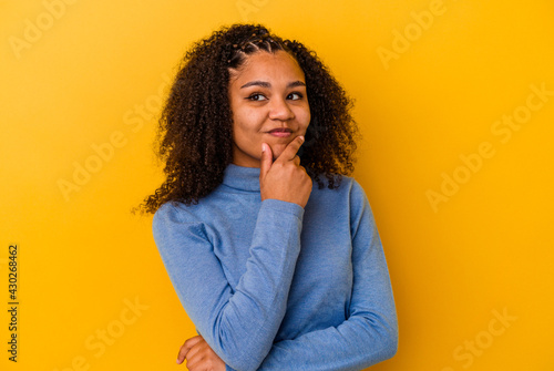 Young african american woman isolated on yellow background thinking and looking up, being reflective, contemplating, having a fantasy. © Asier