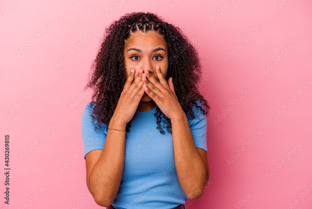 Young african american woman isolated on pink background shocked, covering mouth with hands, anxious to discover something new. Young african american woman isolated on pink background shocked, covering mouth with hands, anxious to discover something new.