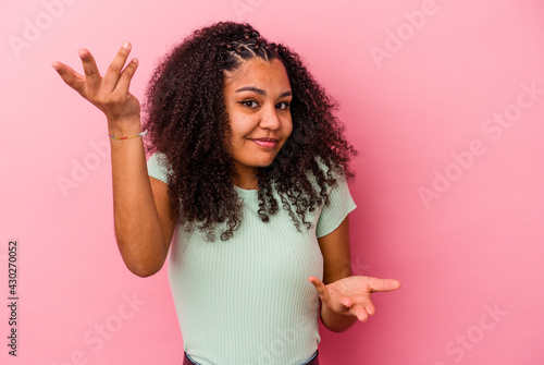 Young african american woman isolated on pink background makes scale with arms, feels happy and confident.