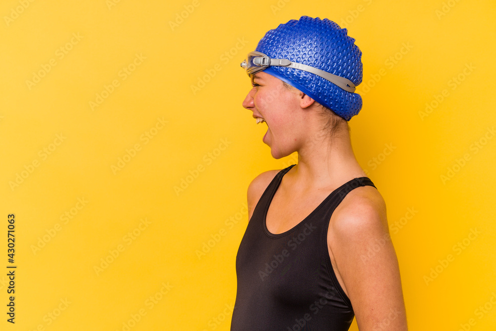 Young swimmer venezuelan woman isolated on yellow background shouting towards a copy space Young swimmer venezuelan woman isolated on yellow background shouting towards a copy space