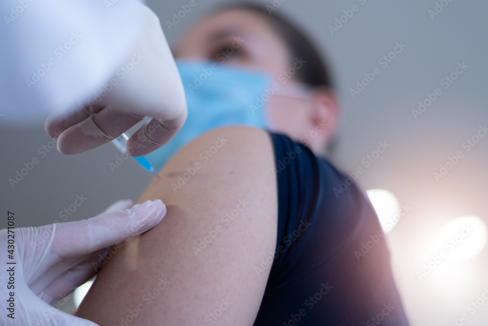 Fototapeta premium Coronavirus vaccination, doctor injecting a patient, getting first shot of covid vaccine in arm muscle. Medical doctor in protective suit and mask, process of immunization against covid-19