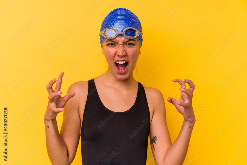 Young swimmer venezuelan woman isolated on yellow background screaming with rage. Young swimmer venezuelan woman isolated on yellow background screaming with rage.