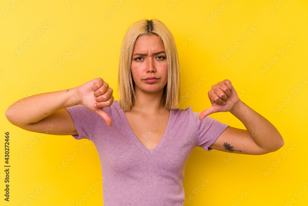 Young venezuelan woman isolated on yellow background showing a dislike gesture, thumbs down. Disagreement concept. Young venezuelan woman isolated on yellow background showing a dislike gesture, thumbs down. Disagreement concept.