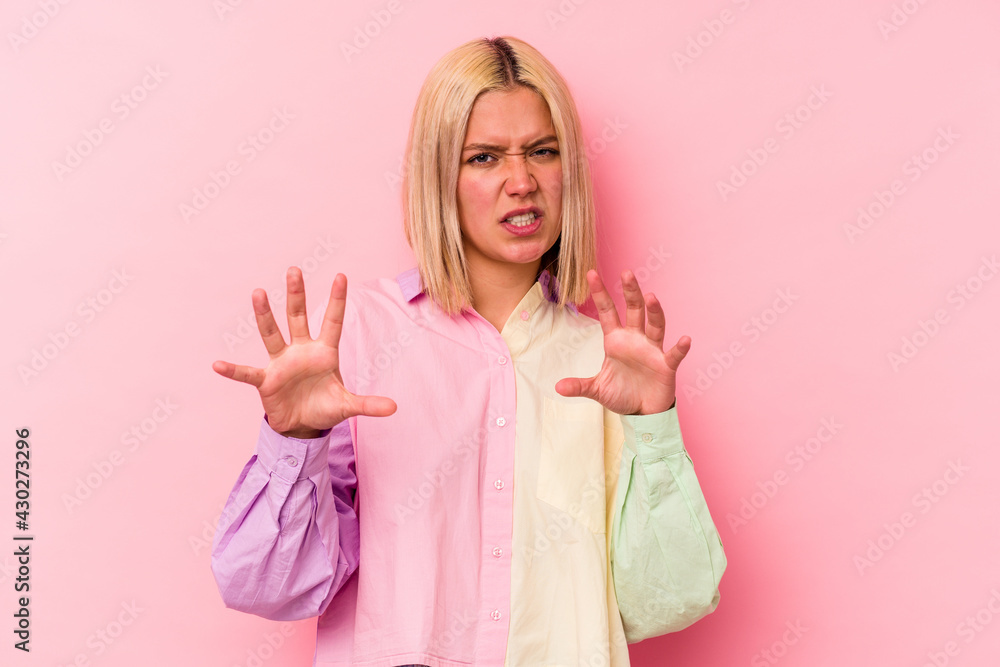 Young venezuelan woman isolated on pink background showing claws imitating a cat, aggressive gesture. Young venezuelan woman isolated on pink background showing claws imitating a cat, aggressive gesture.