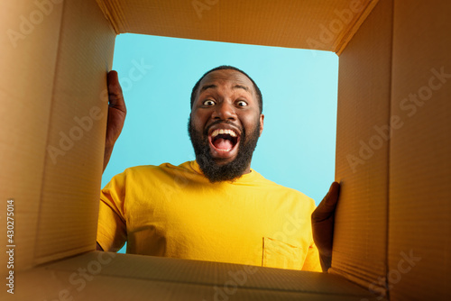 Happy man receives a package from online shop order. happy and surprised expression. cyan background. photo