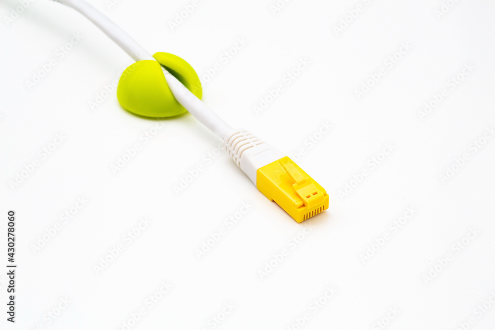 Computer network cable with yellow RJ-45 connector in green cable clip on white background Computer network cable with yellow RJ-45 connector in green cable clip on white background