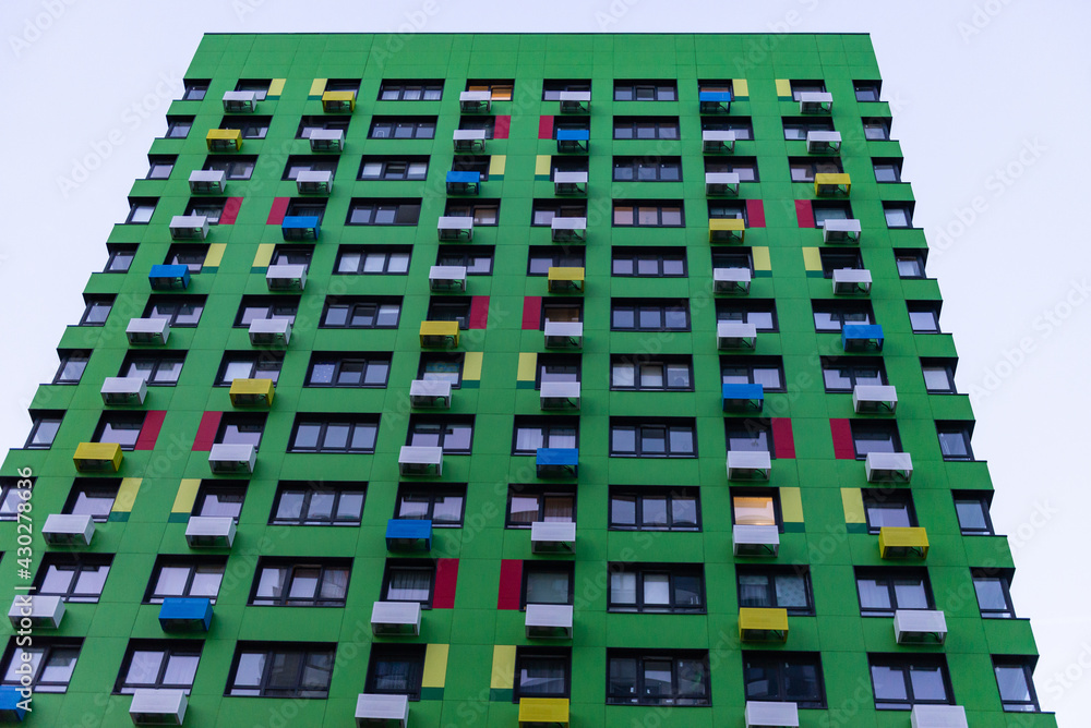 Green facade of a multi-storey building. Multi-colored boxes for air conditioning.