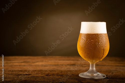 Glass full of cold beer on the wooden table photo