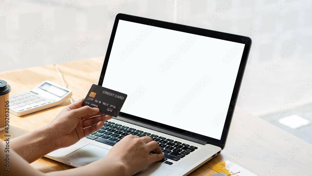 A young woman holds a plastic credit card on her computer in online purchases and online payment sites. A young woman holds a plastic credit card on her computer in online purchases and online payment sites.