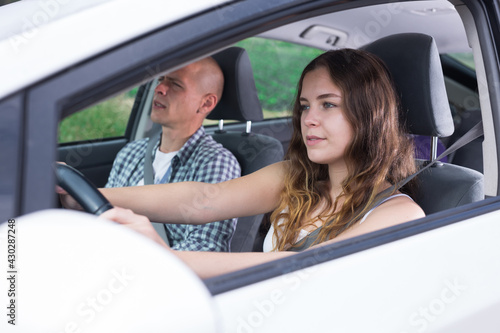 Young attractive girl driving car with man in passenger seat during trip, side view © JackF