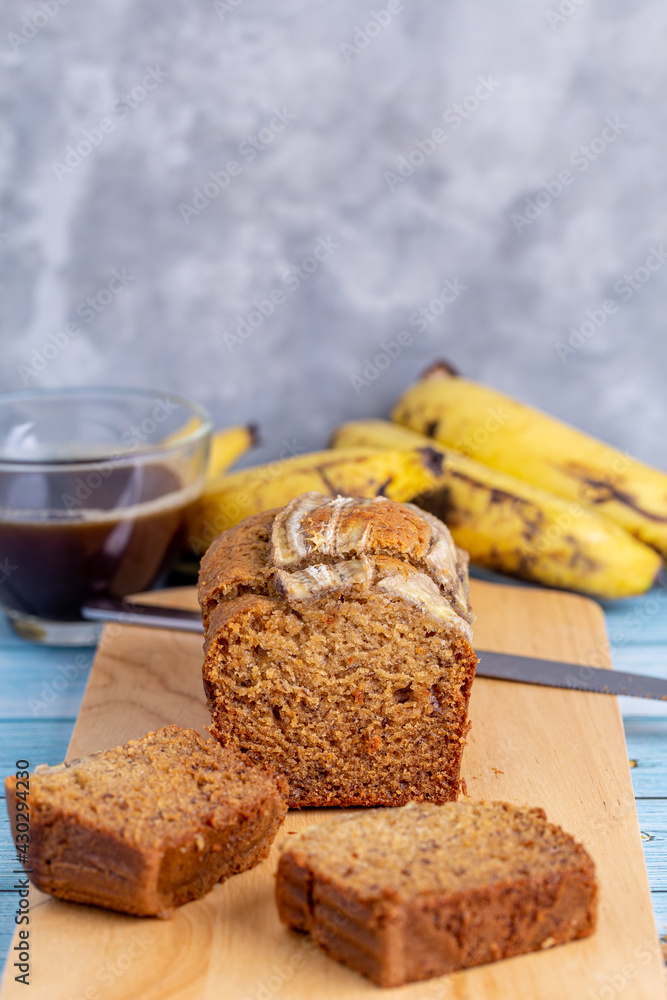 Delicious banana bread sliced on a wooden board with coffee cup on table for breakfast. Delicious banana bread sliced on a wooden board with coffee cup on table for breakfast.