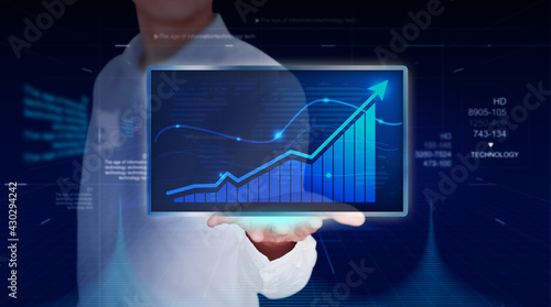 Fényképezés A businessman in a white shirt clutches a tablet computer to analyse sales figures and economic charts
