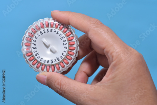 Homone replacement in pill dispenser with date running in woman's hand for treate the Genitourinary syndrome of menopause photo