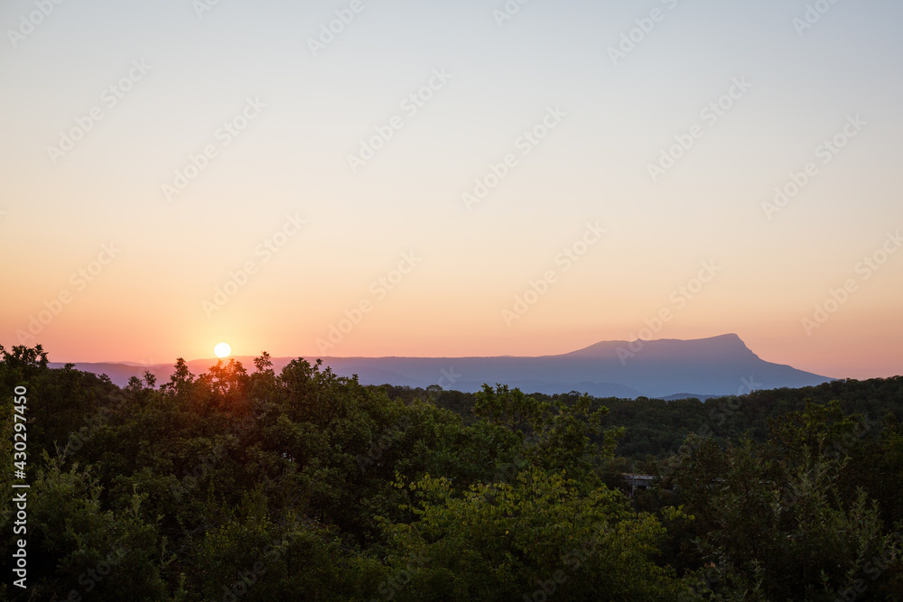 beautiful, evening landscape with mountains and green forest on the background of a crimson sunset