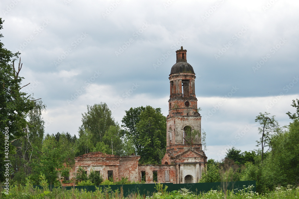 View of an abandoned stone church on the background of the green forests on a gloomy day.