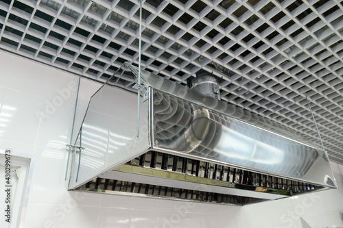 Suspended metal hood against a white wall. Kitchen equipment.