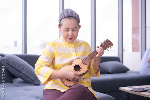 asian grandma play ukulele in living room photo