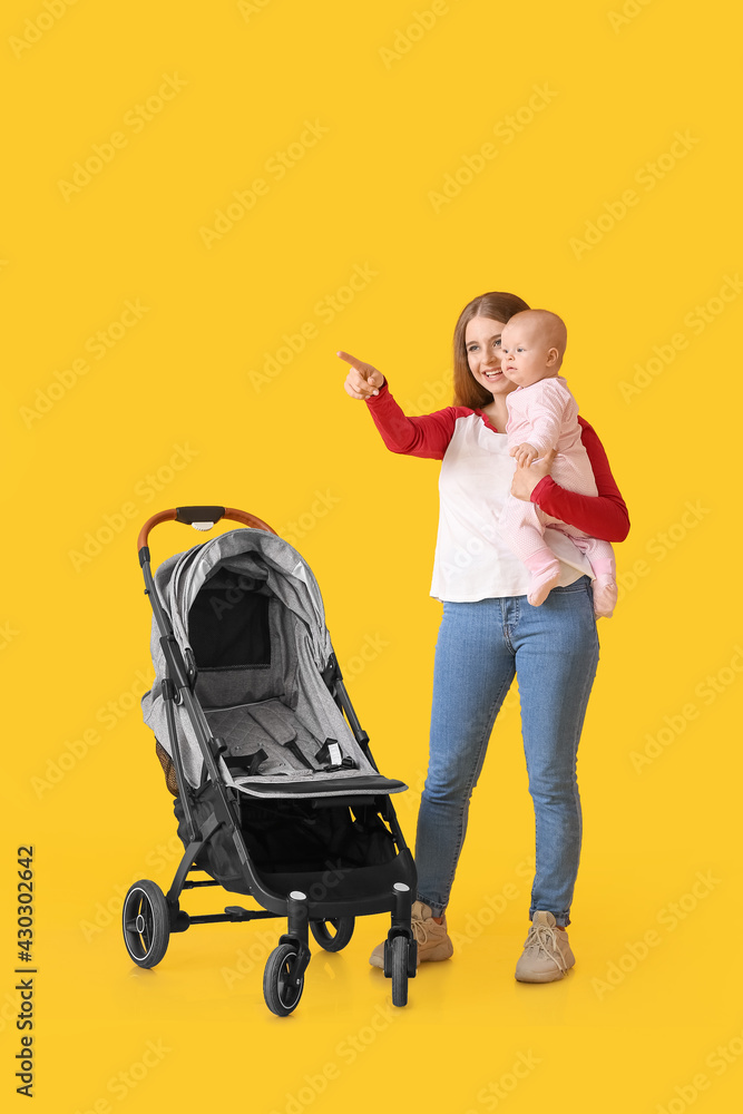 Woman with her cute baby and stroller on color background Woman with her cute baby and stroller on color background