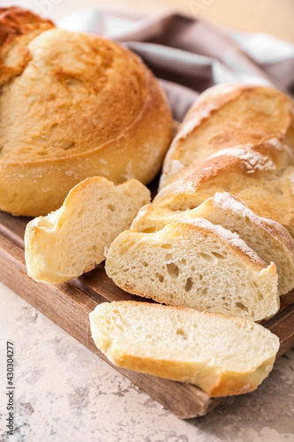 Board with fresh cut bread on grunge background