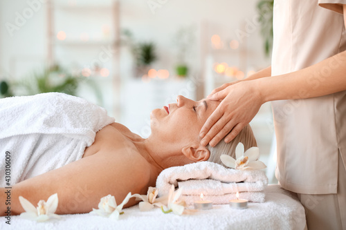 Mature woman receiving face massage in beauty salon