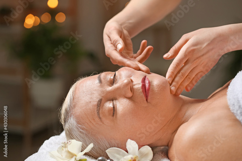 Mature woman receiving face massage in beauty salon