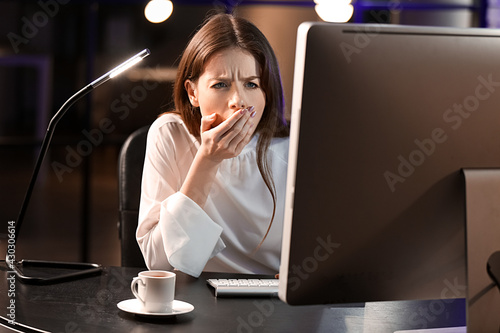 Sleepy young woman using co...