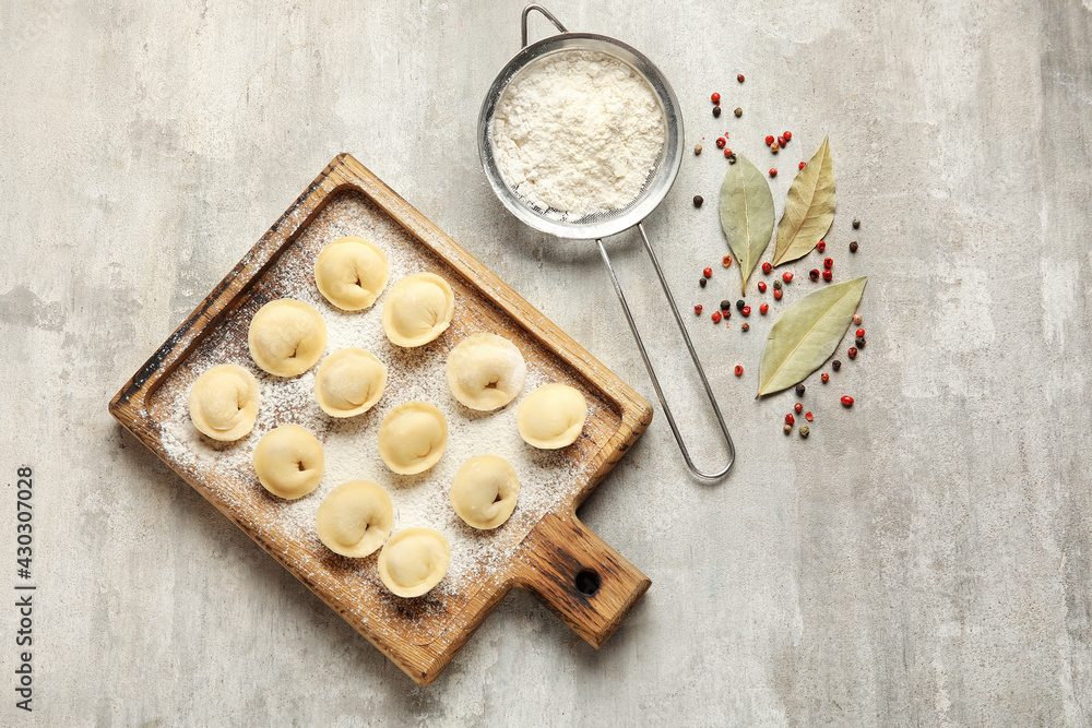 Board with raw dumplings, flour and spices on grunge background Board with raw dumplings, flour and spices on grunge background