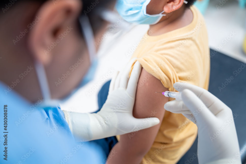 Close up Doctor making a vaccination in the shoulder of patient boy or child person, coronavirus,covid-19 vaccine disease preparing for human clinical trials vaccination shot, Injection on Arm Close up Doctor making a vaccination in the shoulder of patient boy or child person, coronavirus,covid-19 vaccine disease preparing for human clinical trials vaccination shot, Injection on Arm