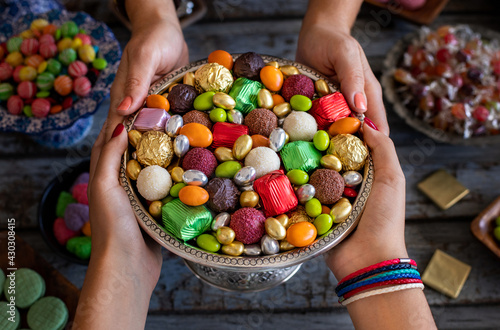 Bowl of candies and chocolate at the hands of two women. Kız isteme ve şeker bayramı ikramı photo