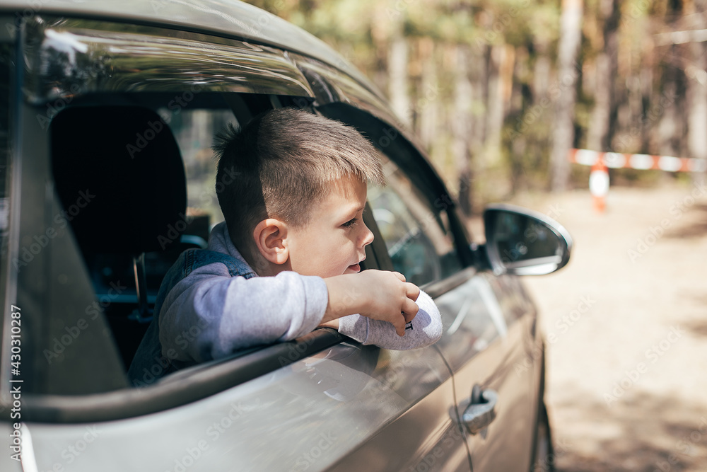 Caucasian preschool boy 6-7 years old in the car looking through window. Travel, vacation concept. Caucasian preschool boy 6-7 years old in the car looking through window. Travel, vacation concept.