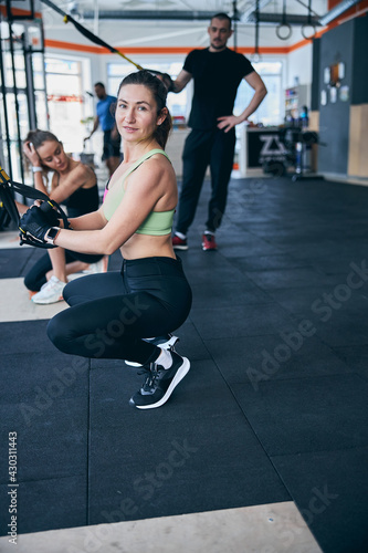 Fototapeta Naklejka Na Ścianę i Meble -  Calm sportswoman posing at the gym among her fitness partners