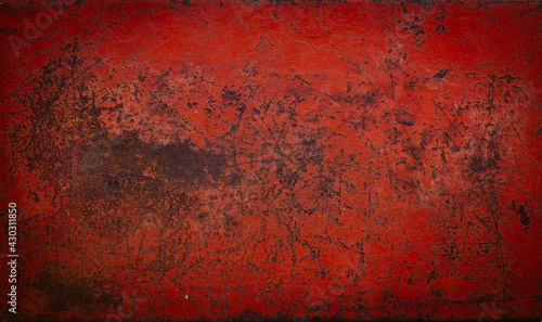 The surface of the old red metal is scratched and corroded to rust.