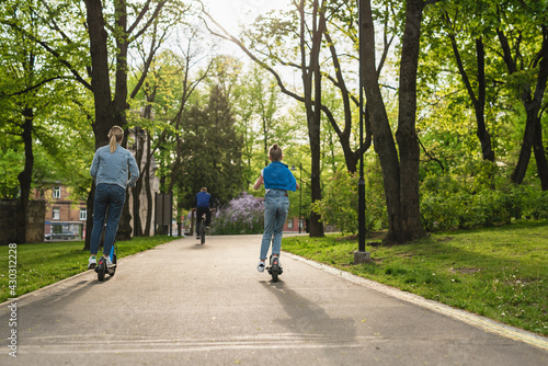 Mother and daughter riding electric scooters  in city park