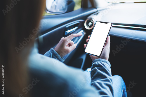 Mockup image of a woman holding and using mobile phone with blank screen in the car
