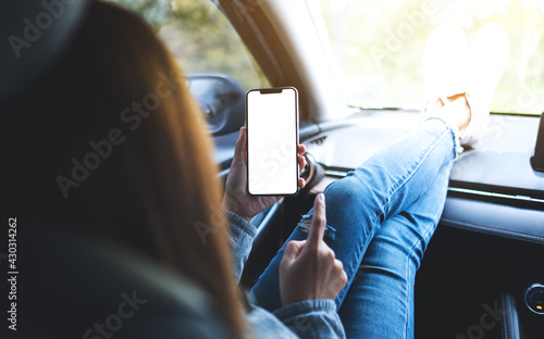 Mockup image of a woman holding and using mobile phone with blank screen in the car