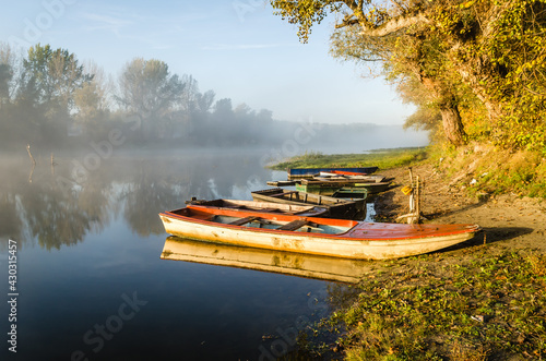 Novi Sad, Serbia - October 22, 2015: A small natural lake near the city of Novi Sad. Wooden fishing boats moored on the shores of the lake, illuminated by the first morning sun.
