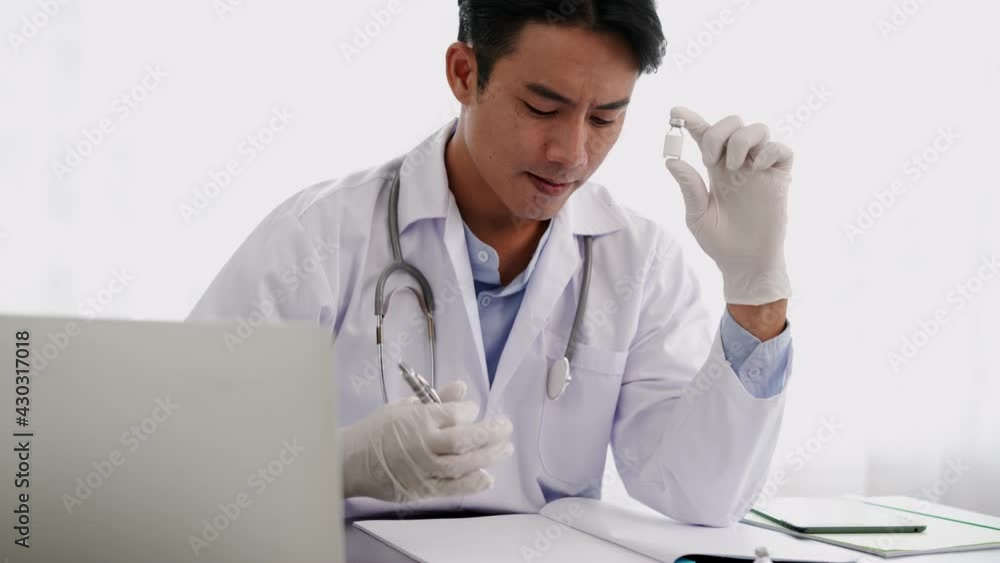 Young Doctor man putting on surgical glove hold vaccine bottle Young Doctor man putting on surgical glove hold vaccine bottle