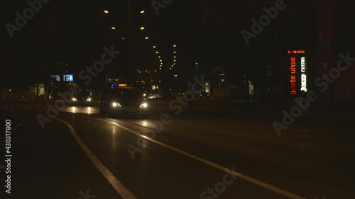 Police cars guiding a special transport on a road at night. Wide shot of tricks with heavy load driving towards the camera. Police cars with blue lights in the front. German road at night. photo
