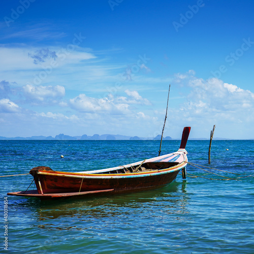 Old Thai wooden boats. Traditional tropical seascape. Traditional wooden longtail taxi boat. Fishing boat docked off the coast of the blue sea.