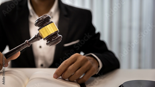 Man judge hand holding gavel to bang on sounding block in the court room. Close up of lawyer holding gavel at desk. Man holding wooden gavel in the hand.