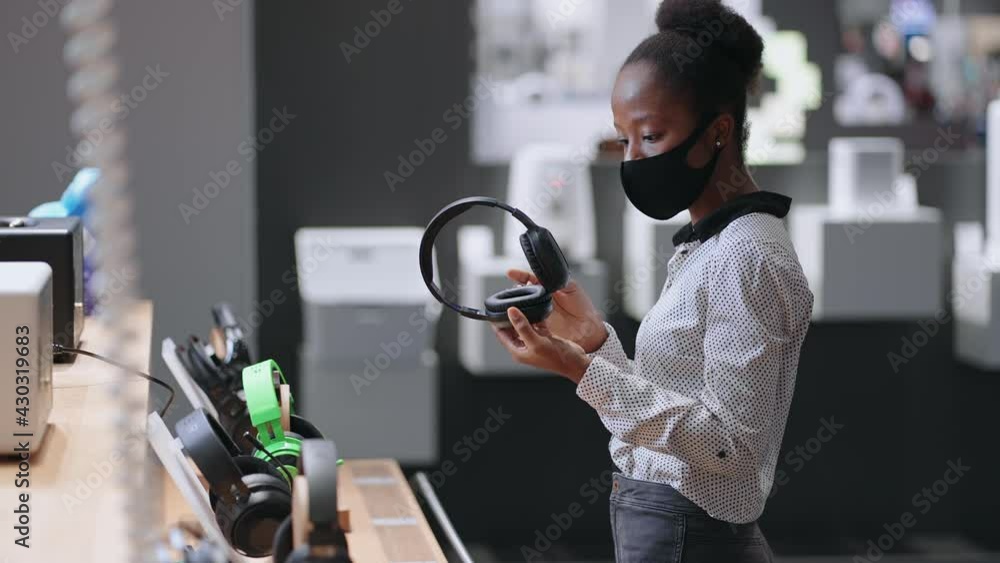 music lover woman is buying headphones in audio equipment store, choosing new model in trading hall of appliance shop music lover woman is buying headphones in audio equipment store, choosing new model in trading hall of appliance shop