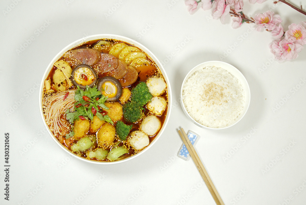Hot pot is also called Malatang, containing ingredients such as mushrooms, ham, vegetables. Rice, a pair of chopsticks on white board, top view Hot pot is also called Malatang, containing ingredients such as mushrooms, ham, vegetables. Rice, a pair of chopsticks on white board, top view