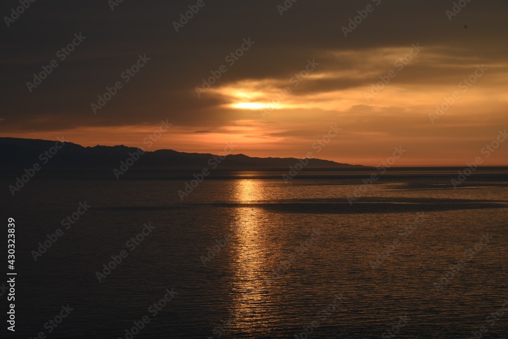 Golden sun rays making their way through the clouds, Golden reflection on the water Golden sun rays making their way through the clouds, Golden reflection on the water