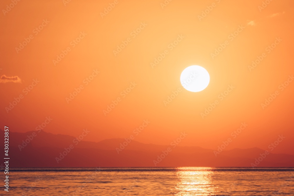 Minimalistic sunrise over the sea. Hazy morning, sun rising above the horizon, background, copy space 