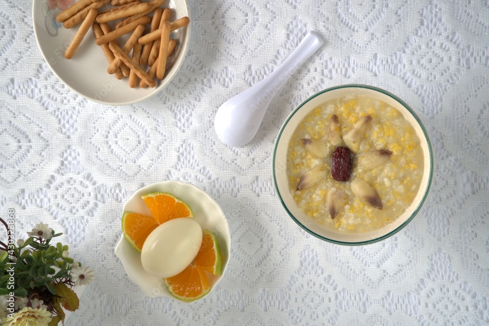 Healthy and nutritious lily red dates porridge, eggs, finger biscuits, oranges, spoon. Top view, white background Healthy and nutritious lily red dates porridge, eggs, finger biscuits, oranges, spoon. Top view, white background