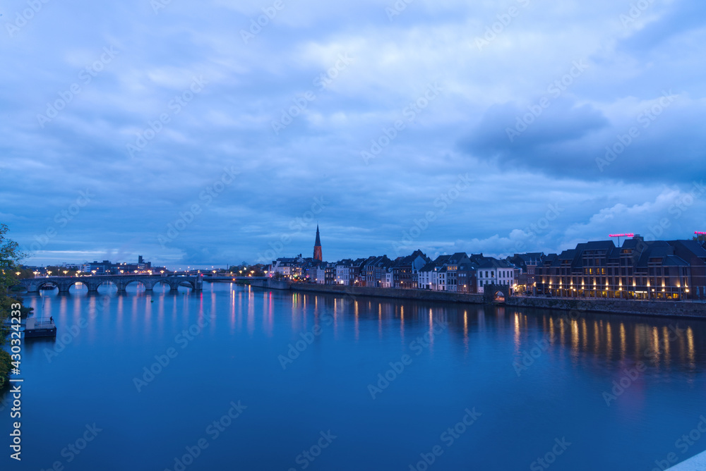 Buildings by sea reflected in water, night view of beautiful seaside city