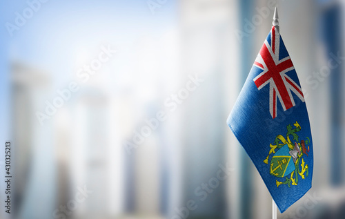 A small flag of Pitcairn Islands on the background of a blurred background photo