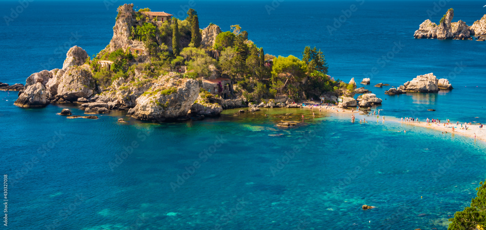 Crystal clear blue green waters surrounding the little island of Isola Bella in Taormina, Sicily. Panorama, copy space