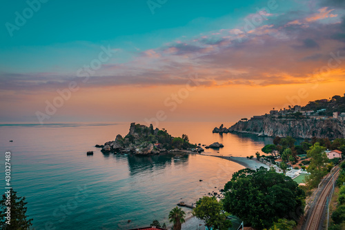 Fototapeta Naklejka Na Ścianę i Meble -  Beautiful sunset scenery over the small island of Isola Bella in Taormina, Sicily.  Teal and orange theme 
