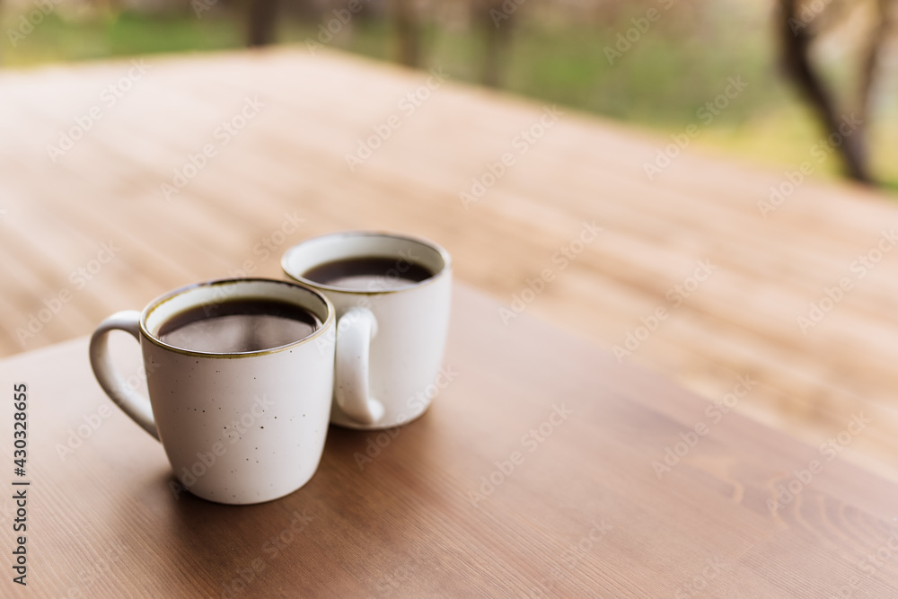Two cups of coffee on the table on the wooden brown terrace Two cups of coffee on the table on the wooden brown terrace